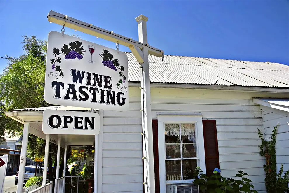 A sign that says wine tasting is posted outside of the building.