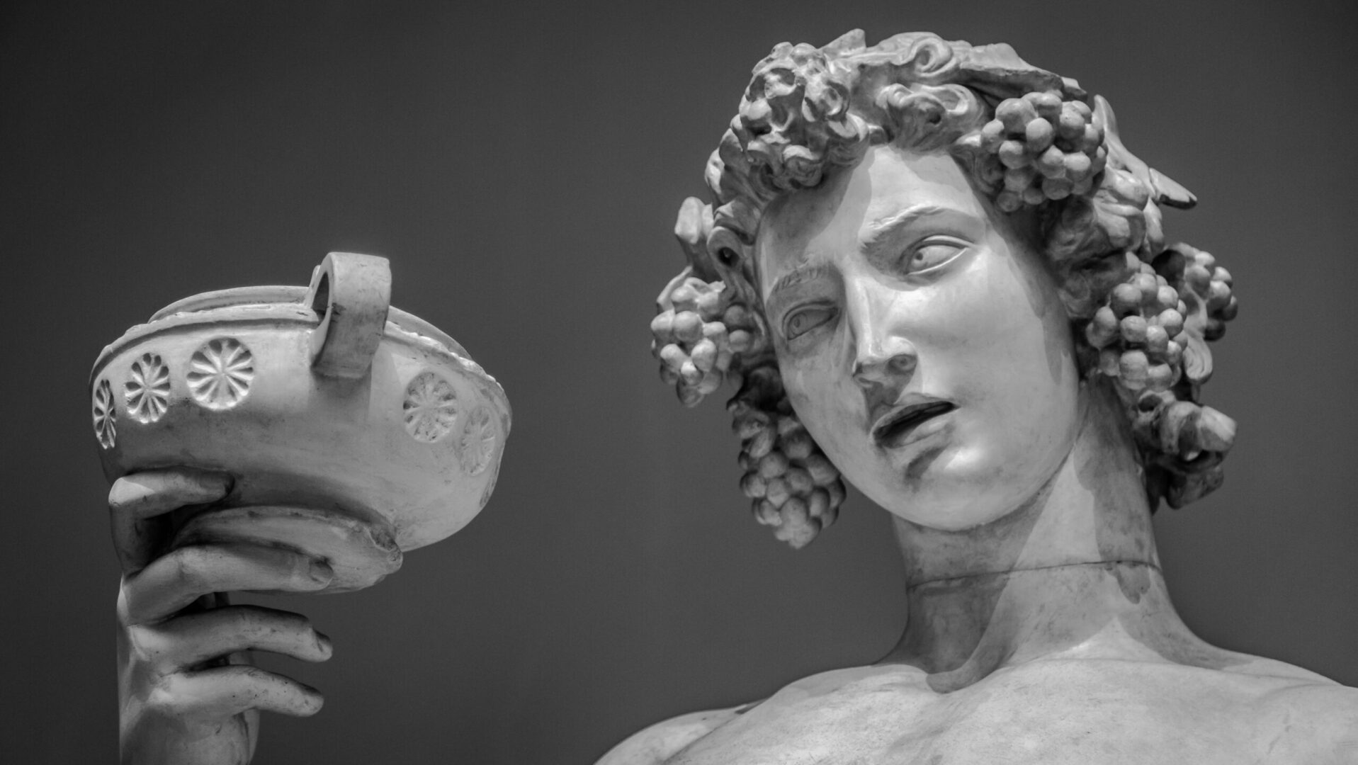 A statue of a man with curly hair and a mirror.