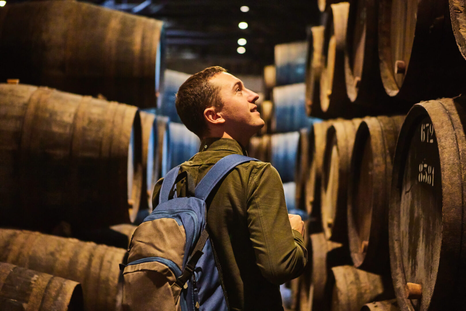 A man standing in front of many barrels.